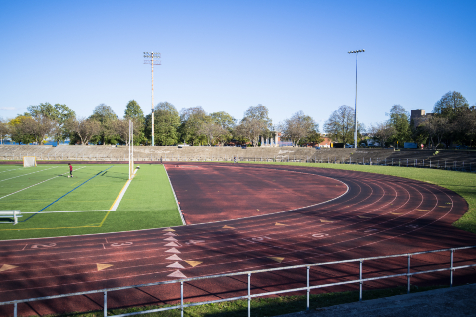 A community running track beside a multipurpose sports field
