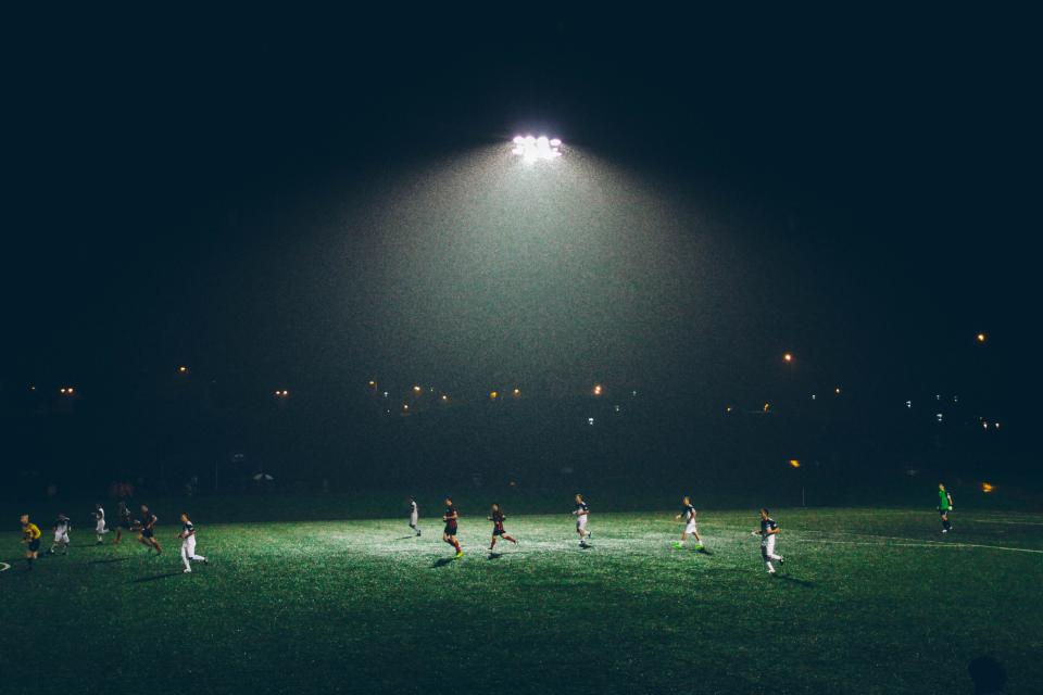Players competing under field lights during an evening match